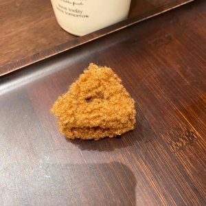 Dettaglio di un fermaglio per capelli a triangolo marrone in lana su vassoio di legno