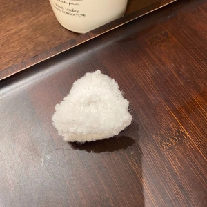 Dettaglio di una molletta triangolare in peluche bianco su un vassoio di legno
