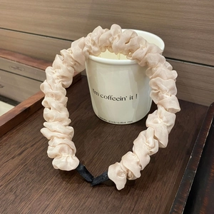 Nahaufnahme des champagnerfarbenen Scrunchie-Haarreifs mit elegantem Plissee-Stoff