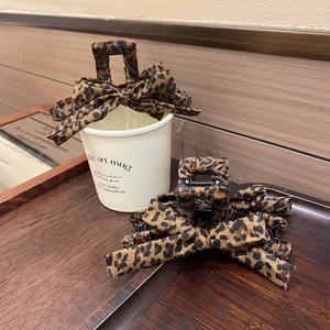 Detailed view of leopard print bow hair claws on wood table with a latte cup