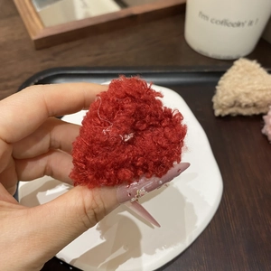 Dettaglio di un fermaglio per capelli a cuore rosso in peluche morbido per acconciature