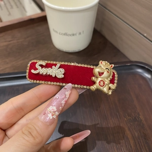 Detailaufnahme einer roten Samt-Haarklammer mit Smile-Strass und goldener Drachenfigur