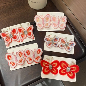 Détail de barrettes papillon brodées à la main avec perles et pierres précieuses