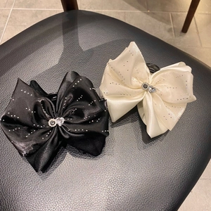Détail de pinces à cheveux à gros nœuds avec texture satin de soie et strass brillants