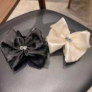 Détail de pinces à cheveux en satin noir et ivoire ornées de strass brillants élégants