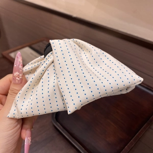 Close-up of white fabric hair claw with blue polka dots and premium bow design