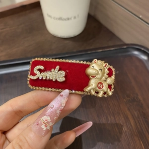 Detail einer roten Samt-Haarspange mit goldenem Smile-Text und chinesischem Sternzeichen-Pferd