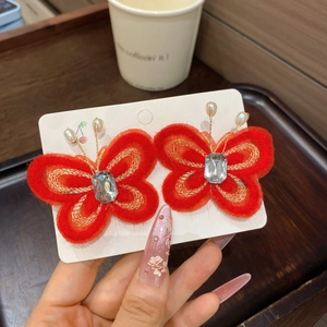 Vue détaillée de pinces à cheveux papillon rouges avec broderie dorée et accents de perles