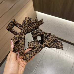 Detail showing the textured leopard print fabric and butterfly bow design on hair claw clips
