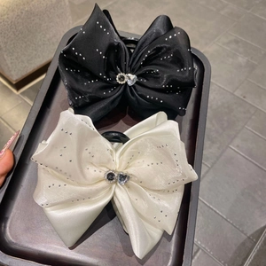Détail de pinces à cheveux en satin avec strass étincelants et boucle en forme de cœur