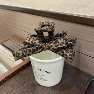 Detail view of a vintage leopard print bow hair claw clip placed on a white coffee mug