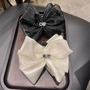 Détail de pinces à cheveux élégantes en satin avec strass et gemmes en cœur sur plateau bois