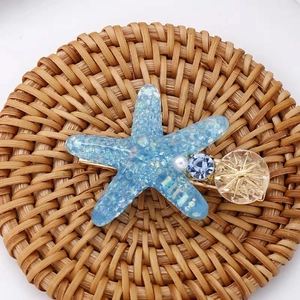 Détail d'une pince à cheveux étoile de mer bleue avec paillettes de résine et perles