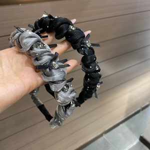 Detail of twist-rope headband with silk texture, black bows and sparkling rhinestones