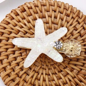 Détail de la pince à cheveux étoile de mer avec strass en cristal sur une base en métal doré