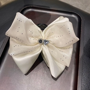 Détail de la pince à cheveux noeud en satin blanc avec strass et coeur en cristal