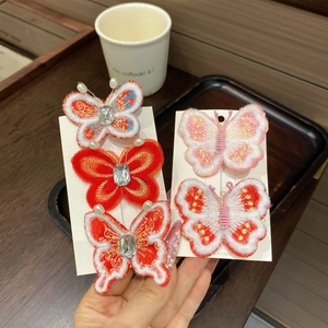 Détail de pinces à cheveux papillon brodées rouges avec perles et strass pour filles