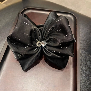 Détail d'une pince à cheveux à nœud en satin noir avec strass et cristaux en cœur