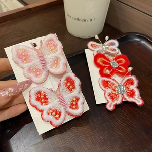 Détail de pinces à cheveux papillon rouges et roses avec broderies, perles et strass