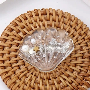 Détail d'une pince à cheveux coquillage avec perles et étoile sur dessous de plat tressé