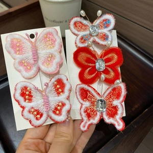 Détail de pince à cheveux papillon rouge avec broderie, fourrure blanche et perles
