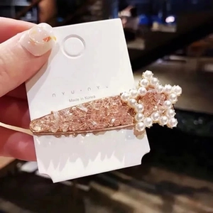 Close-up of star hair clip with pearls and rose gold glitter finish on display card