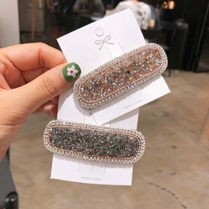 Sparkling crystal encrusted hair clips in champagne gold and gunmetal grey on a white card