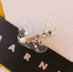 Détail d'une pince à cheveux coquillage en résine, éclats d'argent, perles et étoile