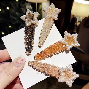 Star-shaped hair clips with crystals and pearls in four assorted colors on display