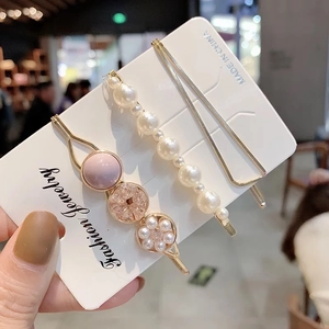 Dettaglio del set di tre fermagli per capelli con perle finte e perline rosa su carta