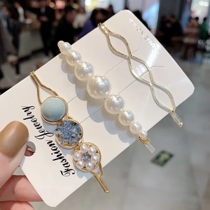 Dettaglio di un set di tre fermagli per capelli con perle bianche e pietre blu dorate
