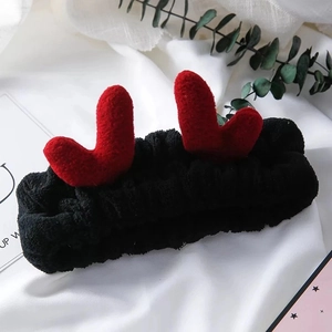 Détail du bandeau en peluche noir avec cœurs rouges sur fond de tissu blanc doux