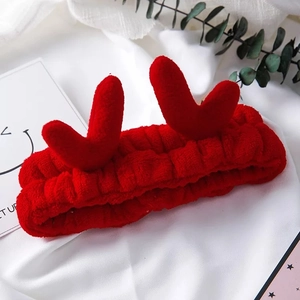 Détail du bandeau en peluche rouge avec bois en forme de cœur sur fond de tissu blanc doux