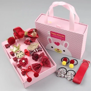 Detail van rode haarstrikken en kroon haarelastiekjes in een roze geschenkdoos
