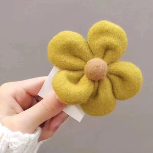 Detailed view of handmade yellow felt flower hair clip with a soft pink core