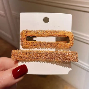 Detailed close-up of amber orange hair clip set with sparkling beads and gold metal base