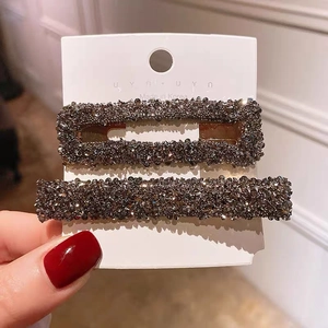 Detailed close-up of two pieces vintage hair clips with shimmering crystals in dark grey