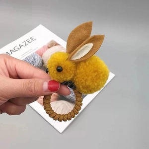 Détail d'élastique à cheveux lapin en peluche jaune avec oreilles et bande spirale