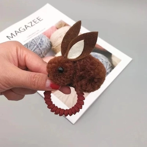 Détail d'élastique à cheveux avec lapin en peluche marron et bande spirale rouge foncé
