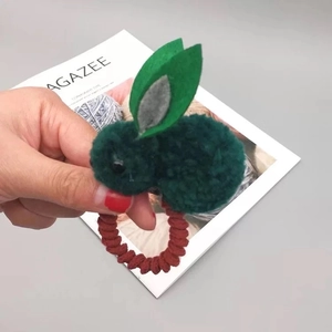 Gros plan sur un élastique à cheveux lapin en peluche vert foncé avec spirale rouge
