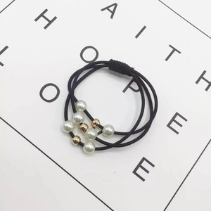 Detailed view of three-strand elastic hair tie with white pearls and gold beads