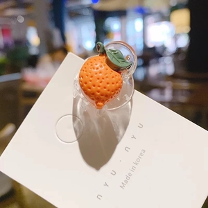 Détail d'une mini pince à cheveux en forme d'orange avec texture en résine et feuilles vertes
