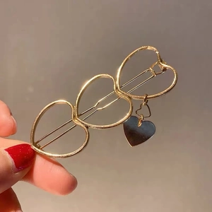 Fermaglio per capelli in metallo dorato con tre cuori traforati e un piccolo ciondolo
