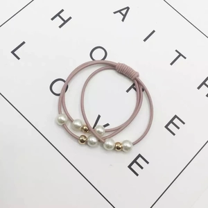 Detail of pink elastic hair bands with white faux pearls and gold beads on white background
