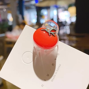 Détail d'une petite pince à cheveux tomate en résine brillante sur une carte