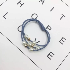 Detail of blue triple-strand elastic hair tie with white pearls and gold bead accents