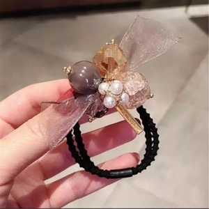 Détail d'un élastique à cheveux avec perles nacrées, perles ambrées et nœud organza