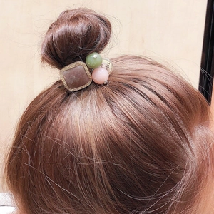 Détail d'un élastique rétro avec carré en résine marron et perles colorées sur cheveux