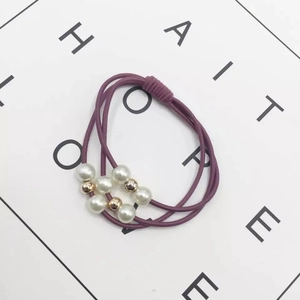Detail of elastic hair ties featuring white faux pearls and gold metal beads set