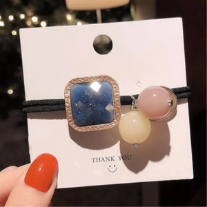 Détail d'un élastique à cheveux avec cristal carré bleu et perle rose élégante